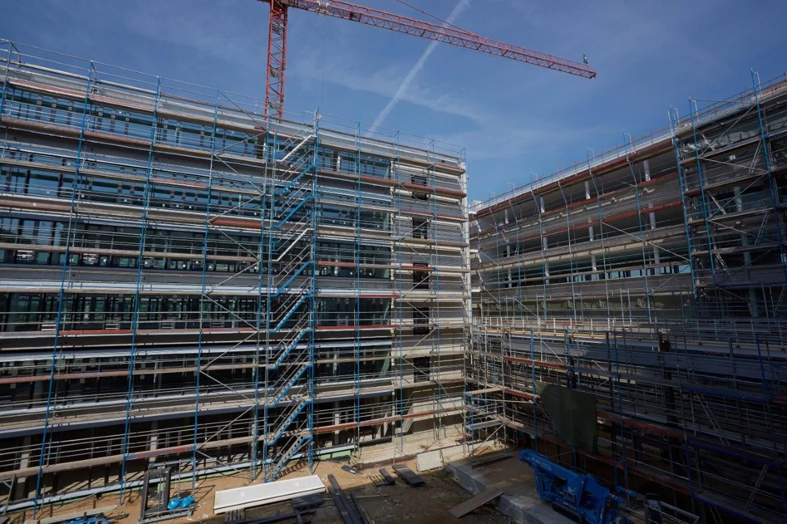 Innenhof desselben Verwaltungsneubaus, beide Gebäudeflügel eingerüstet, Baumaterial und Kran über dem Rohbau